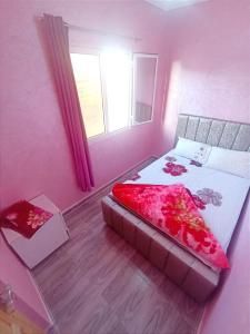 a pink bedroom with a bed and a window at Classico Apartments in Tan-Tan Plage