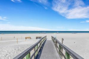 a boardwalk leading to a beach with the ocean at Oceanview - Steps to Beach - King Suite - Pool - Arcade in Clearwater Beach +37 photos