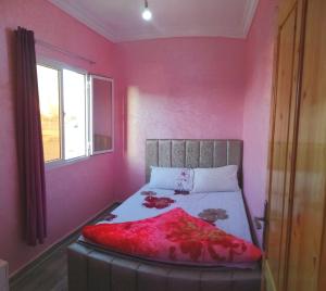 a bedroom with pink walls and a bed with a red blanket at Classico Apartments in Tan-Tan Plage