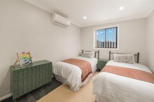 a bedroom with two beds and a window at Pacific Palms Retreat - Entire Home in Plumpton Sleeps 9 - 8-Car Parking Near Eastern Creek in Rooty Hill +23 photos