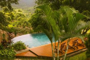 a swimming pool with chairs and a house at Pousada Vale do Dinossauro in São Pedro