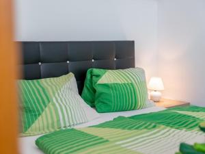 a bed with green and white pillows and a lamp at Selmas in Zell am See