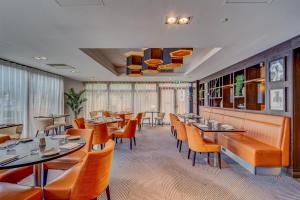 a restaurant with orange chairs and tables and windows at DoubleTree by Hilton London Ealing in London