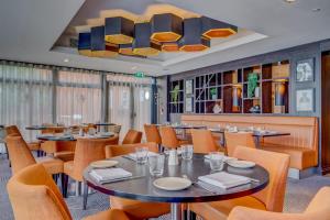 a restaurant with tables and chairs and a chandelier at DoubleTree by Hilton London Ealing in London