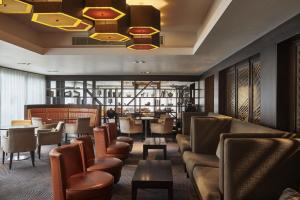 a restaurant with brown chairs and tables and a chandelier at DoubleTree by Hilton London Ealing in London +175 photos