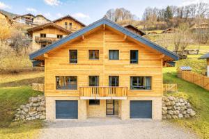 a log home with a deck on a hill at Chalet cosy et neuf, Grande Terrasse, Vue panoramique in Saint-Jean-de-Sixt