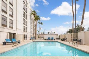 a swimming pool with chairs and a building at Hampton Inn Phoenix-Chandler in Chandler