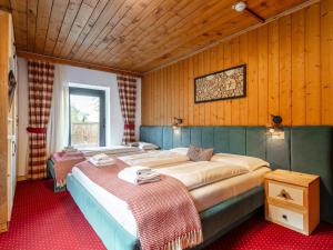 a bedroom with two beds in a room with wooden walls at Bergzeit Hollersbach L in Hollersbach im Pinzgau