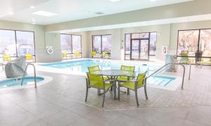 a pool with a table and chairs in front of a pool at Hampton Inn Williamsport in Williamsport