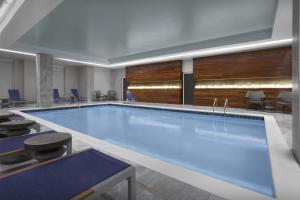 a large swimming pool in a lobby with chairs and tables at Embassy Suites by Hilton Jackson North Ridgeland in Ridgeland