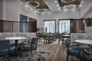 a dining room with tables and chairs and windows at Embassy Suites by Hilton Jackson North Ridgeland in Ridgeland
