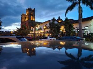 a building with a clock tower and cars parked in a parking lot at Hotel Mision Santa Barbara in Barichara