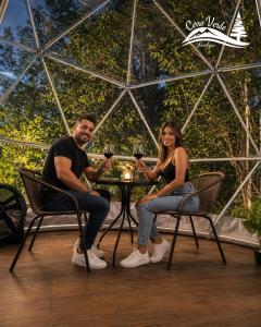 a man and woman sitting at a table with glasses of wine at Cerro Verde Glamping Cartago in Lourdes