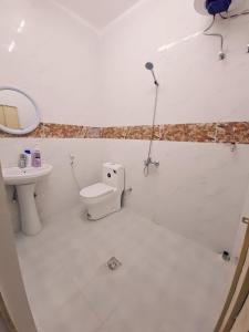 a white bathroom with a toilet and a sink at Easy Stay in Al Ain