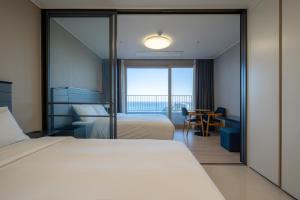 a bedroom with two beds and a table with a view at Hotel The Blue Terra in Sokcho