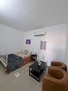 a bedroom with a bed and two chairs and a table at Easy Stay in Al Ain