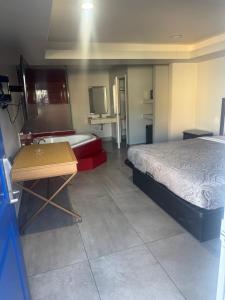 a bedroom with a bed and a tub and a table at Clover motel in Lynwood