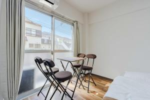 a bedroom with a table and chairs in front of a window at Inage Good Place House in Chiba