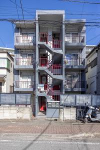 an apartment building with red balconies and a motorcycle parked in front at Inage Good Place House in Chiba