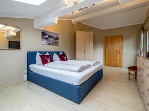 a large bedroom with a blue bed with red pillows at Haslau Large in Hopfgarten im Brixental +28 photos
