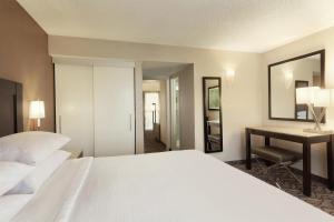 a bedroom with a bed and a desk and a mirror at Embassy Suites by Hilton Arcadia-Pasadena Area in Arcadia +30 photos