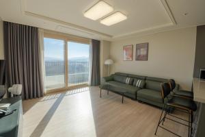a living room with a couch and a large window at Hotel The Blue Terra in Sokcho