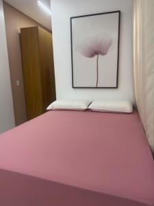 a bedroom with a pink bed with a picture on the wall at Lua prime residence in Petrolina