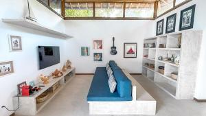 a living room with a blue couch and a tv at Orixás Residence -Casa Yemanja Morro in Cairu