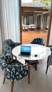 a laptop computer sitting on a white table with chairs at Orixás Residence -Casa Yemanja Morro in Cairu
