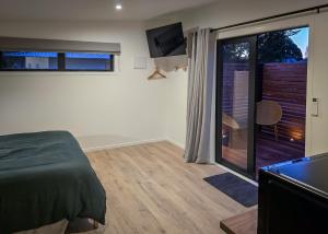 a bedroom with a bed and a sliding glass door at Guesthouse on Gardiners in Christchurch