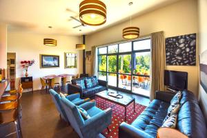 a living room with blue couches and a dining room at Copper Gate in Mapua