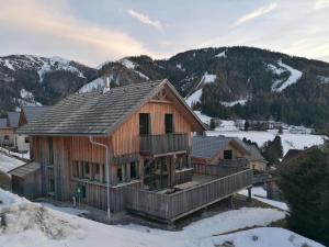 Eine Blockhütte im Schnee mit Bergen im Hintergrund in der Unterkunft Die Bergliebe in Hohentauern
