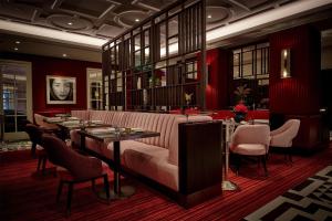 a restaurant with a pink couch and tables and chairs at Conrad London St James in London