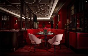 a red restaurant with a table and white chairs at Conrad London St James in London