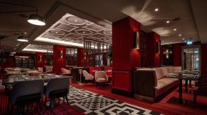 a restaurant with red walls and tables and chairs at Conrad London St James in London +162 photos