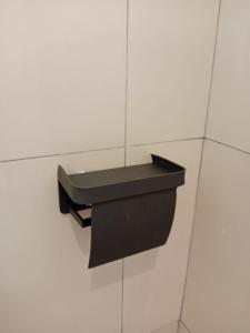 a black toilet paper dispenser on a white tiled wall at Benang Kelambu Cottage in Praya