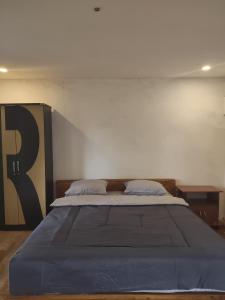 a bedroom with a large bed with blue sheets at Benang Kelambu Cottage in Praya