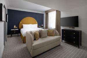 a hotel room with a bed and a couch at The Waldorf Hilton in London