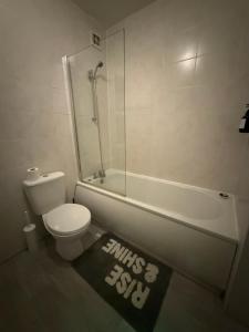 a bathroom with a toilet and a tub and a shower at City Apartment in Litherland