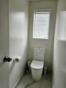 a white toilet in a bathroom with a window at 27 Alpine Avenue in Hanmer Springs +17 photos