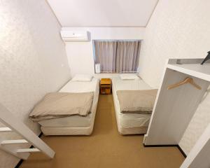 a small room with two beds and a window at Nikko TEN Stay in Nikko