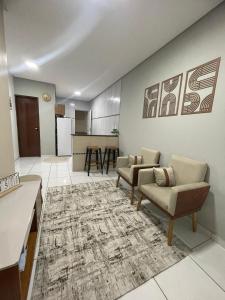 a living room with two chairs and a kitchen at Apto do xavier III in Petrolina