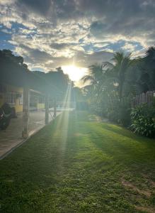 a grassy area with the sun shining through the trees at Casa Shekinah in Araruama