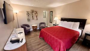 a hotel room with a bed with a red bedspread at Sage N Sand Motel in Moses Lake