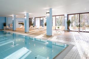 a pool in a hotel with chairs and tables at DoubleTree by Hilton Luxembourg in Luxembourg