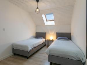 two beds in a attic bedroom with a window at De Marckhoeve in Merksplas