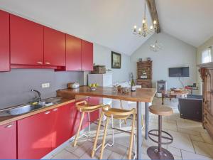 a kitchen with red cabinets and a table with stools at Quanto B in Geetbets +11 photos