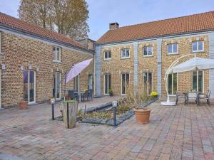 a brick building with a courtyard with tables and an umbrella at Quanto A in Geetbets