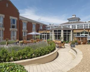 a building with a courtyard with tables and benches at Hilton Northampton Hotel in Northampton