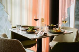 a table with two plates of food and glasses of wine at Hilton Paris La Défense in Puteaux